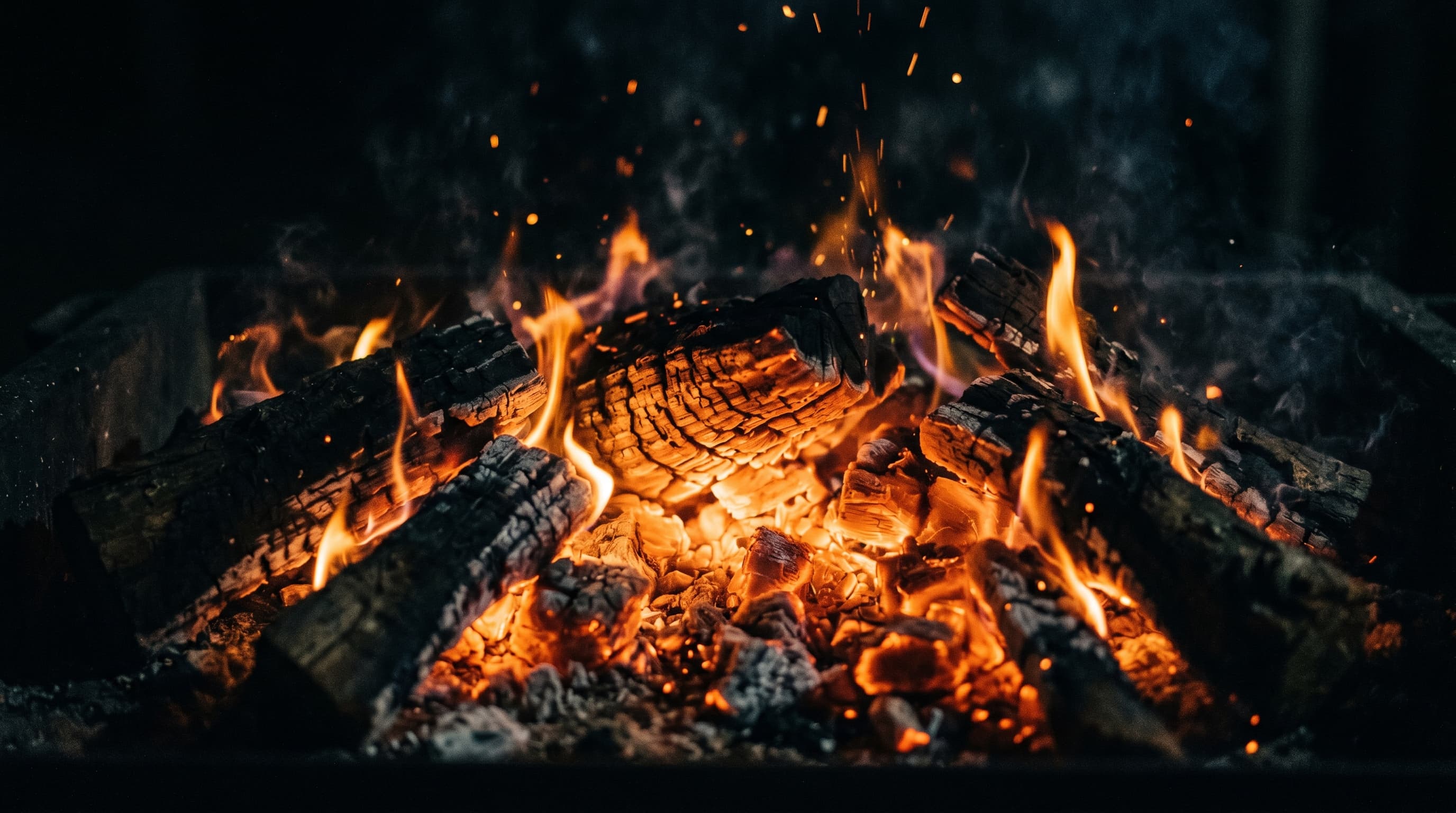 Glowing braai coals and flames over burning hardwood